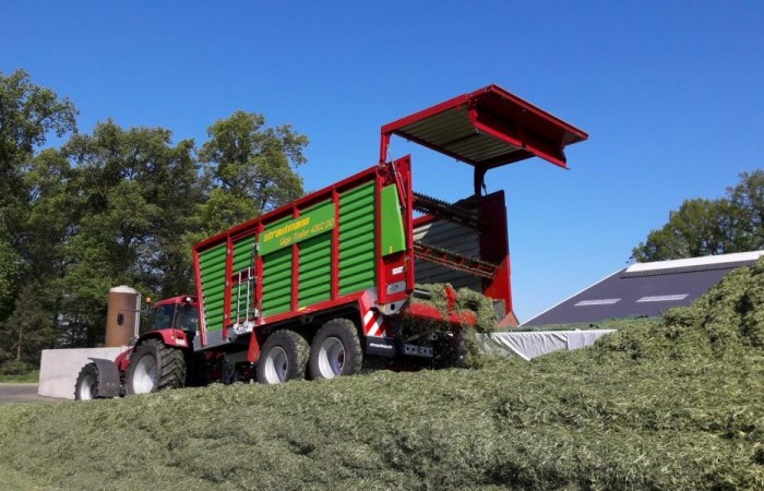Der Silagewagen verteilt das Gras auf dem Silo